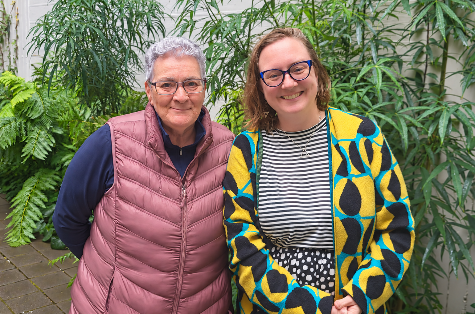 Brenda Bryan and Sasa smiling together among green plants